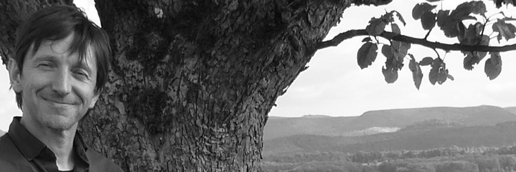 Auf dem Bild ist Harald Sickinger unter einem Obstbaum auf den Härten zu sehen. Im Hintergrund sieht man die Schwäbische Alb.
